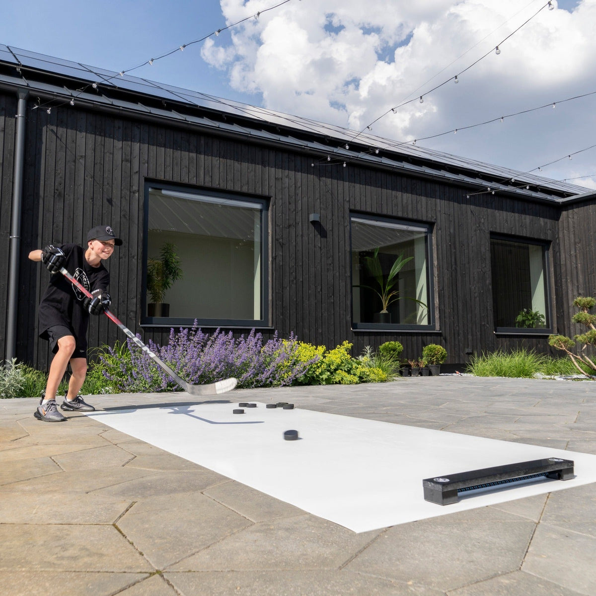 Hockey player training catch-and-shoot repetitions with a rebounder on a garden shooting surface