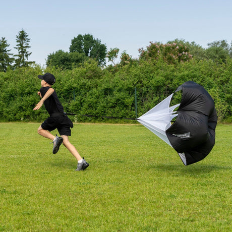 Young hockey player sprinting outdoors with a speed chute for resistance training