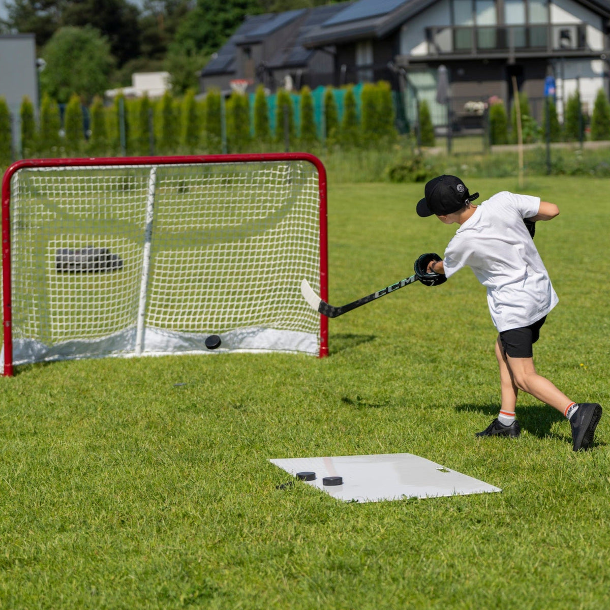 Young hockey player practising shots in the garden on a shooting pad