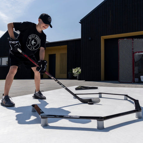 Young hockey player focusing on stickhandling drills in a garden, building confidence through repetition