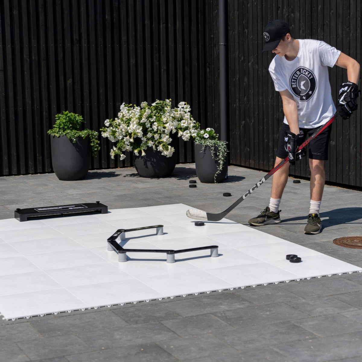 Hockey player in trainers training stickhandling with a puck on slick training tiles at home